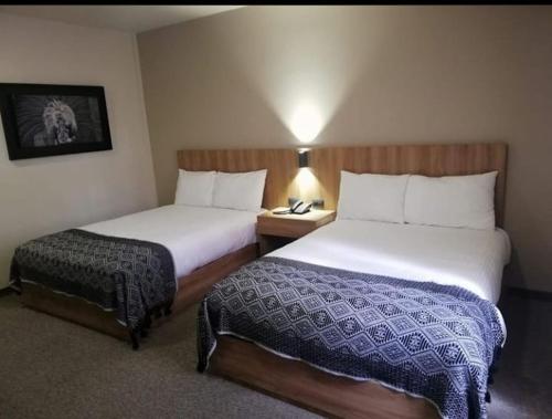 a hotel room with two beds and a table with a lamp at Hotel San Francisco Tlaxcala in Tlaxcala de Xicohténcatl