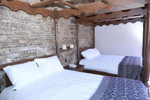 a bedroom with two beds and a brick wall at Hotel San Francisco Tlaxcala in Tlaxcala de Xicohténcatl