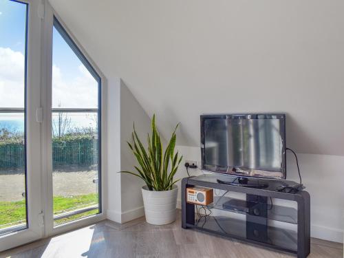 a tv sitting on a stand in a room with a window at Sunny South Lodge in Sandown