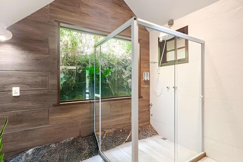 a glass shower in a bathroom with wooden walls at Chalé Montserrat com Lareira e Vista para as Montanhas in Nova Friburgo