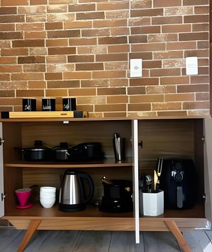 a shelf with pots and pans and a brick wall at Chalé Montserrat com Lareira e Vista para as Montanhas in Nova Friburgo