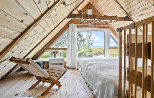a bedroom with a bed and a chair in front of a window at Hyggelig Lille Feriebolig Med Havudsigt in Østerby