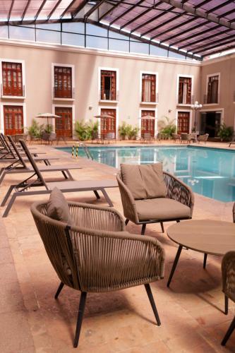 a pool with chairs and tables next to a building at Hotel San Francisco Tlaxcala in Tlaxcala de Xicohténcatl