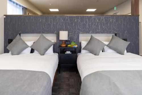 two twin beds in a room with a wall at Otakihashi Pacifica Building in Tokyo