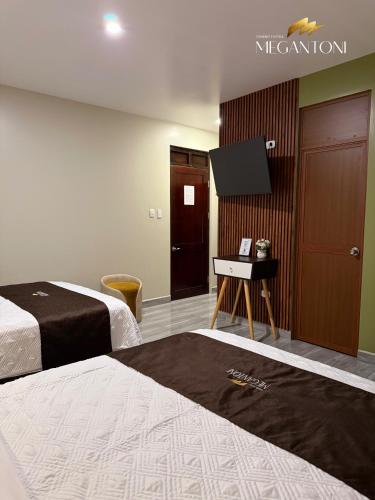 a hotel room with two beds and a flat screen tv at Grand Hotel Megantoni in Quillabamba