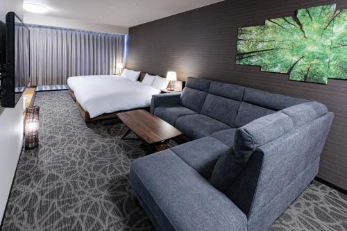 a hotel room with a couch and a bed at Hotel Silk Tree Nagoya in Nagoya