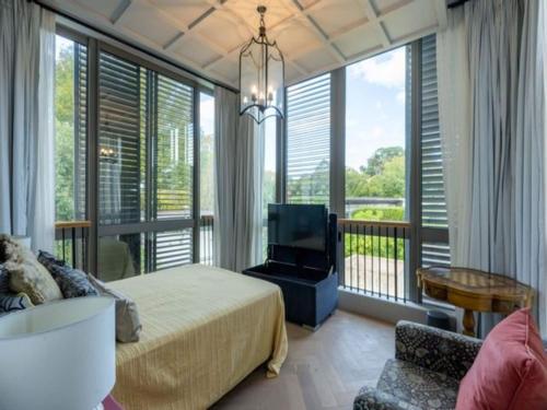 a bedroom with a bed and a balcony with a tv at French Elegance in Bishopscourt in Cape Town