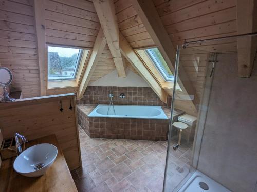 a attic bathroom with a tub and a sink at Borner Holzhaus in Born