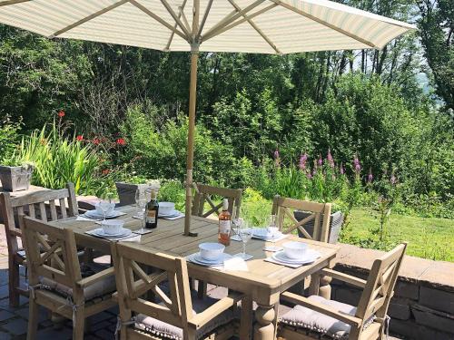 a wooden table with an umbrella in a garden at Clawdd Gwyn in Llanrwst
