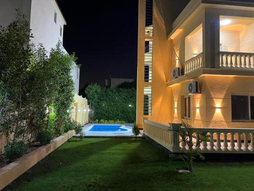 ein Haus mit einem Garten mit einem Swimmingpool bei Nacht in der Unterkunft الاسكندريه كينج مريوط in King Mariout