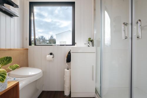 a bathroom with a toilet and a sink and a window at Kiwi Farm Cabin 1 by Tiny Away in Waitoki