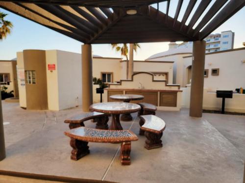 a patio with a table and benches and a building at Beachfront Condo on Sandy Beach, Las Palmas Resort, 24hrs Security, Free Parking, Free Wi-Fi in Puerto Peñasco