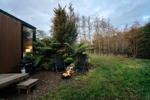 a backyard with two chairs and a fire pit at Kiwi Farm Cabin 2 by Tiny Away in Waitoki