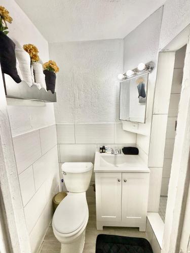 a white bathroom with a toilet and a sink at # 11 Cozy Mini House by the Lake in Canal Point