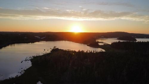 a sunset over a body of water with the sun setting at The Eyrie, your private Ocean View apartment in Head of Jeddore