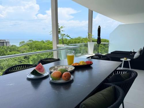 einen Tisch mit zwei Obstteller und einem Glas Orangensaft in der Unterkunft Luxury 2BR Bolongo Ocean View Private Beach in Higuera Blanca