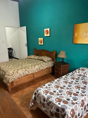 a bedroom with two beds and a blue wall at Apartamento no centro de Paraty in Paraty