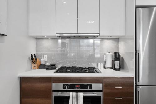 a kitchen with a stove top oven next to a refrigerator at Luxury Waterfront Suite with City Views and AC in Calgary