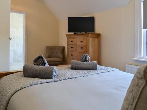 a bedroom with a bed with a tv and a chair at Llwynon Cottage in Llandudno