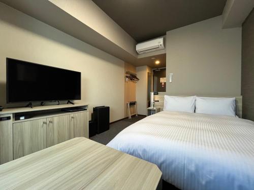 a hotel room with two beds and a flat screen tv at Hotel Route Inn Higashi Matsue in Matsue