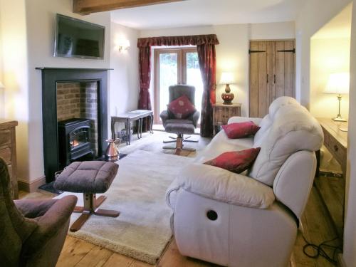 a living room with a white couch and a fireplace at Two Bridge Cottage in Winsham