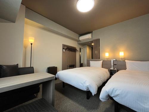 a hotel room with two beds and a table at Hotel Route Inn Higashi Matsue in Matsue