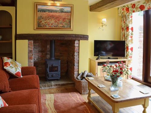a living room with a fireplace and a television at The Landings Cottage in Nun Monkton