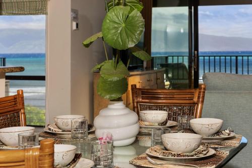 a table with plates and a vase with a plant at Kahana Village 34 · KHV 34 Direct Ocean Front Views 2BD Kahana C in Kahana