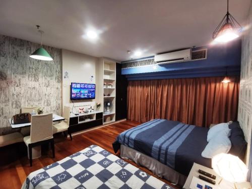 a bedroom with two beds and a desk and a television at Resort Suites Pyramid & Lagoon in Petaling Jaya