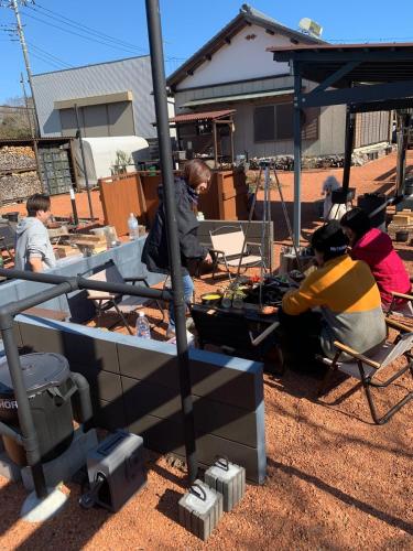 a group of people sitting in chairs under a tent at KAMADOBA glamping in Tōganemachi