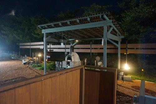 a wooden fence with a gate and a building at night at KAMADOBA glamping in Tōganemachi