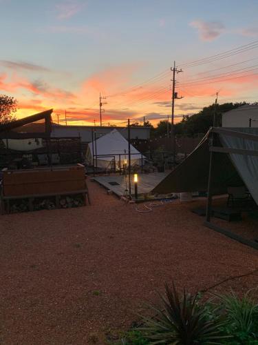 a sunset with a tent and benches in a yard at KAMADOBA glamping in Tōganemachi