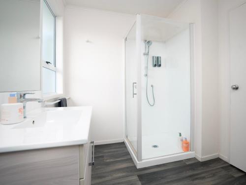 a white bathroom with a shower and a sink at Colonial On Gladstone Motel in Gisborne