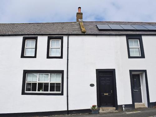 a white house with solar panels on the roof at Alice Cottage in Embleton