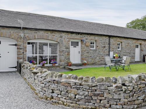 a stone house with a stone wall and a table at Manor Farm Cottage in Carperby