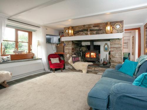 een woonkamer met een blauwe bank en een open haard bij Railway Cottage in Camelford