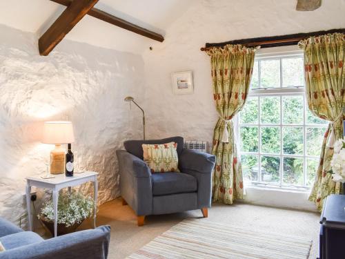 ein Wohnzimmer mit einem Stuhl und einem Fenster in der Unterkunft Scrumpy Cottage in Bodmin