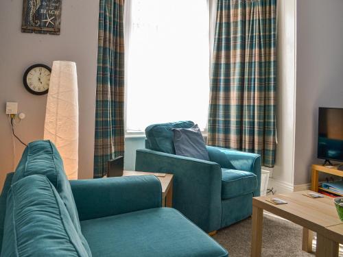 a living room with two blue chairs and a tv at Zack's Seaside Stay in Bridlington