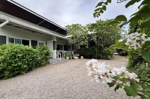 a house with a gravel driveway and flowering plants at Bann Kam B&B in Krabi town