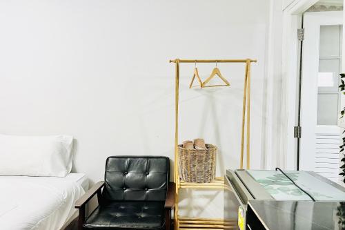 a bedroom with a black leather chair and a glass table at Bann Kam B&B in Krabi town