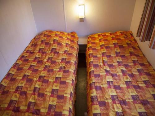 two beds sitting next to each other in a room at Mobil-home 6 pers avec Terrasse à Naucelle - API-1-52-325 in Naucelle