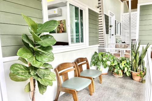 a porch with two chairs and potted plants at Bann Kam B&B in Krabi town
