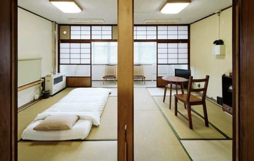 a room with a bed and a table and a chair at 北のくらし研究所 in Rokugō