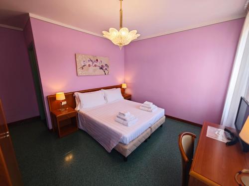 a bedroom with a bed with purple walls and a chandelier at Casa Malvina in Mira