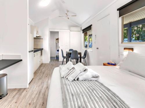 a white bedroom with a large bed and a table at Rockingham Holiday Village in Rockingham