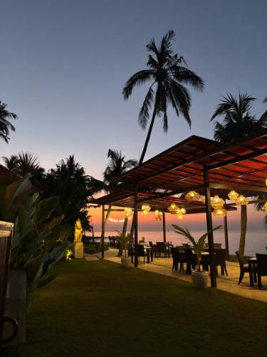 a restaurant on the beach with palm trees and lights at Villa Ganesha Penuktukan in Tejakula