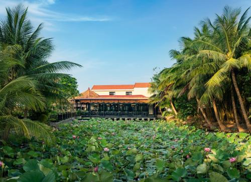 a large pond filled with lots of flowers and palm trees at Sen Village Hoi An in Hoi An