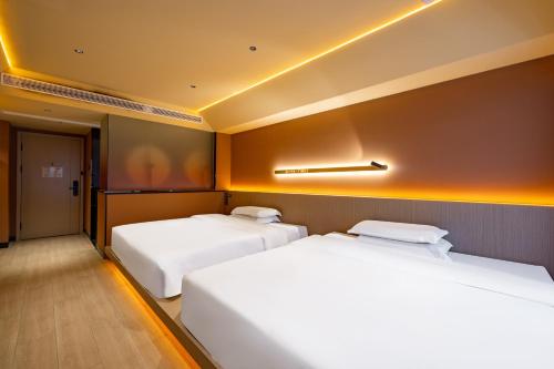 two white beds in a room with at Super Time Trendy Design Hotel Guangzhou Beijing Road Pedestrian Street Dafo Temple Branch in Guangzhou