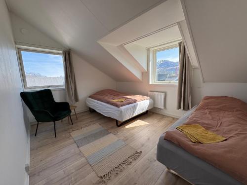 a attic room with two beds and a chair at Helt hus til leje midt i Nuuk in Nuuk