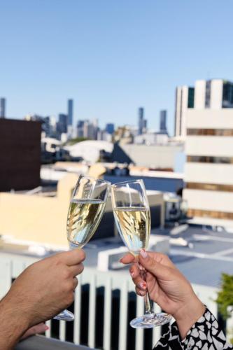 two people holding up glasses of white wine at Jephson Hotel & Apartments in Brisbane